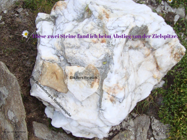 Zwei Steine und zwar ein Herzstein aus weißem Fels und ein Stein, wie die Zielspitze mit einer sieben drin